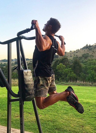 Athlete training pull-ups at sunset